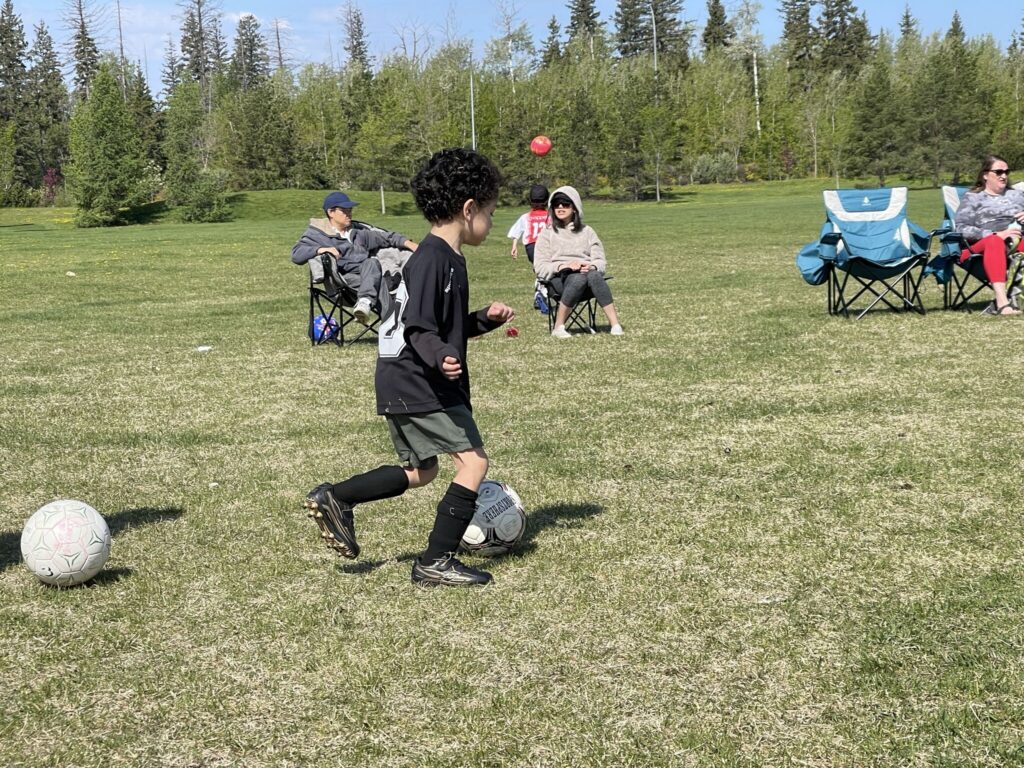 Child playing soccer in Edmonton park representing child-friendly cities